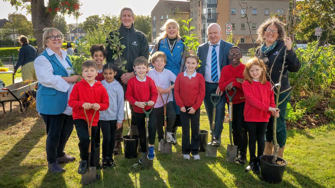 Group of children and adults planting trees.