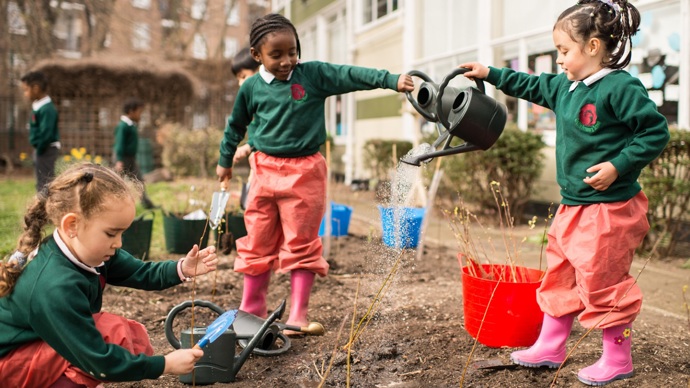 Schoolchildren planting and watering saplings