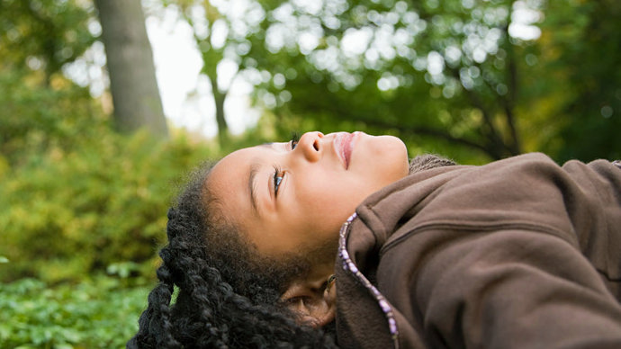 Girl lying on a rock looking up at the trees