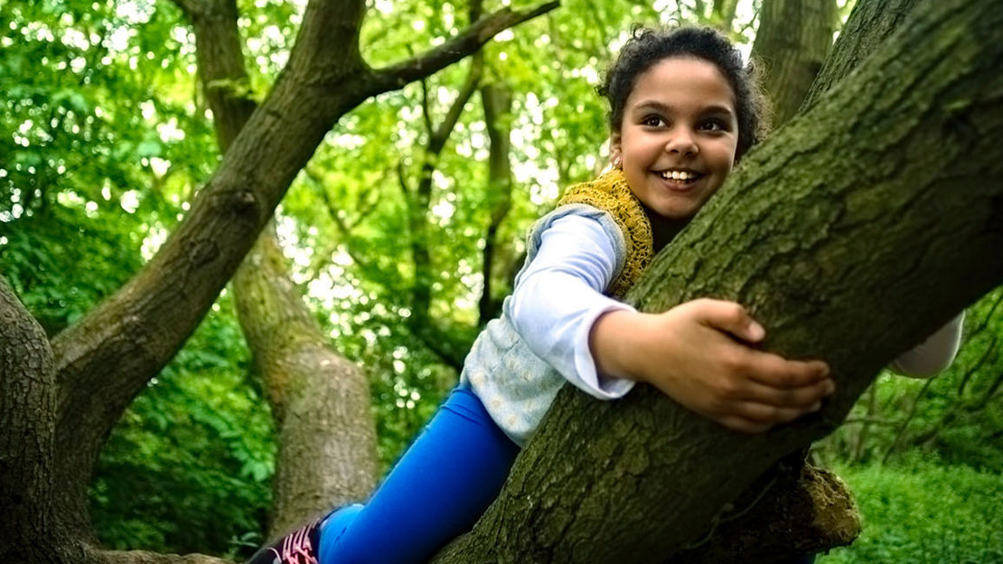 Smiling girl climbing a tree