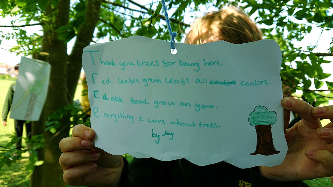 Child holding up their tree poem