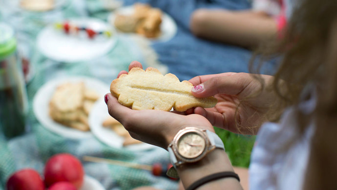 Child holding a biscuit shaped like an oak leaf