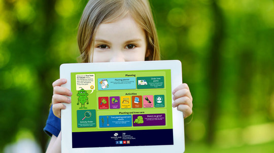 Child holding a tablet showing Tree Tools for Schools on it