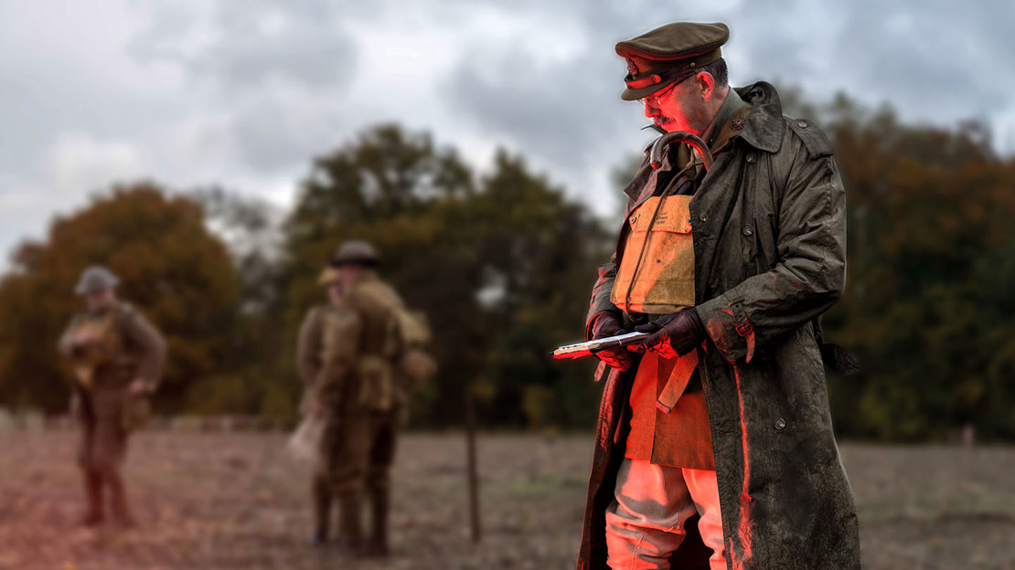 Man dressed in a First World War uniform looking at red glow