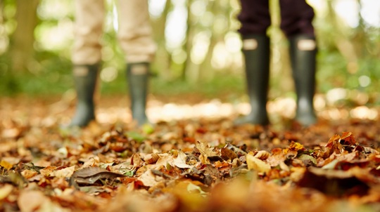 two people with wellies on leafy woodland floor