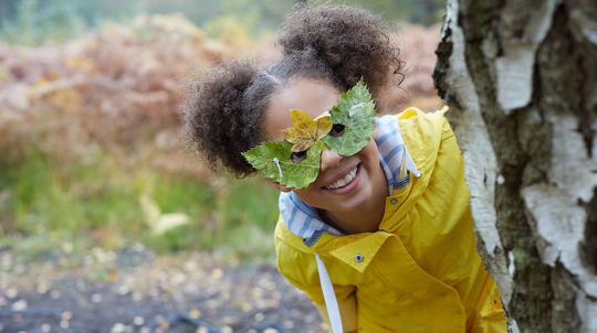 Smiling girl wearing a leafy mask as she plays outside