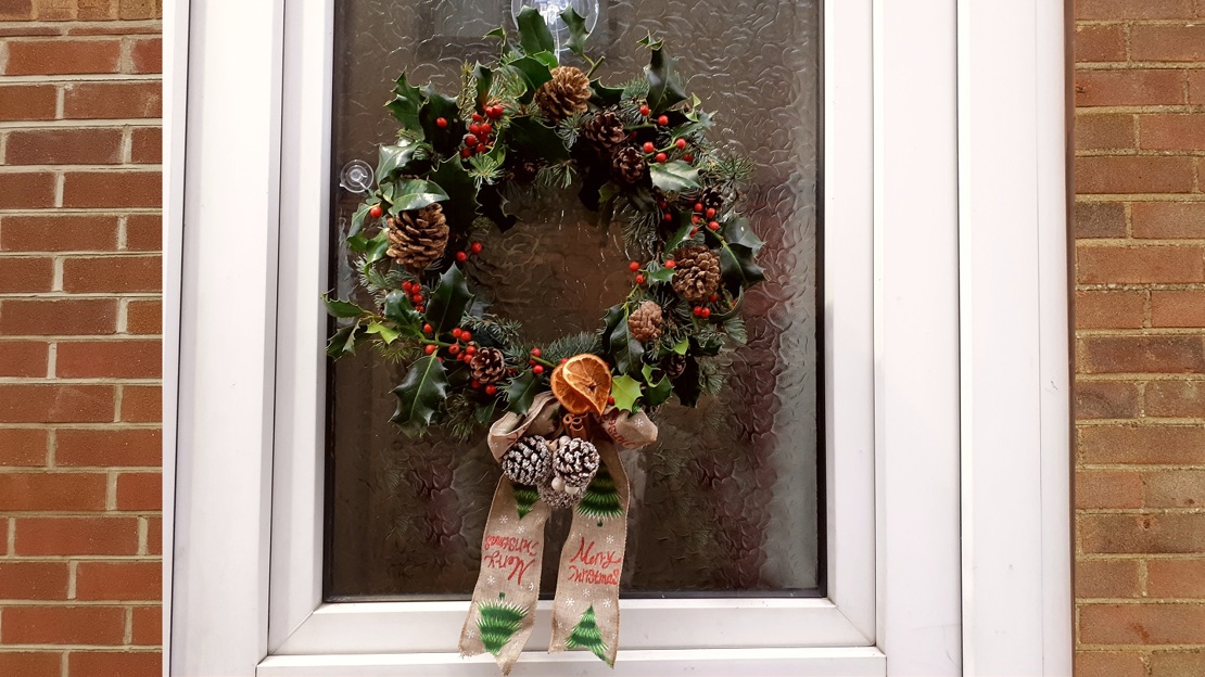 A holly wreath hanging on a front door