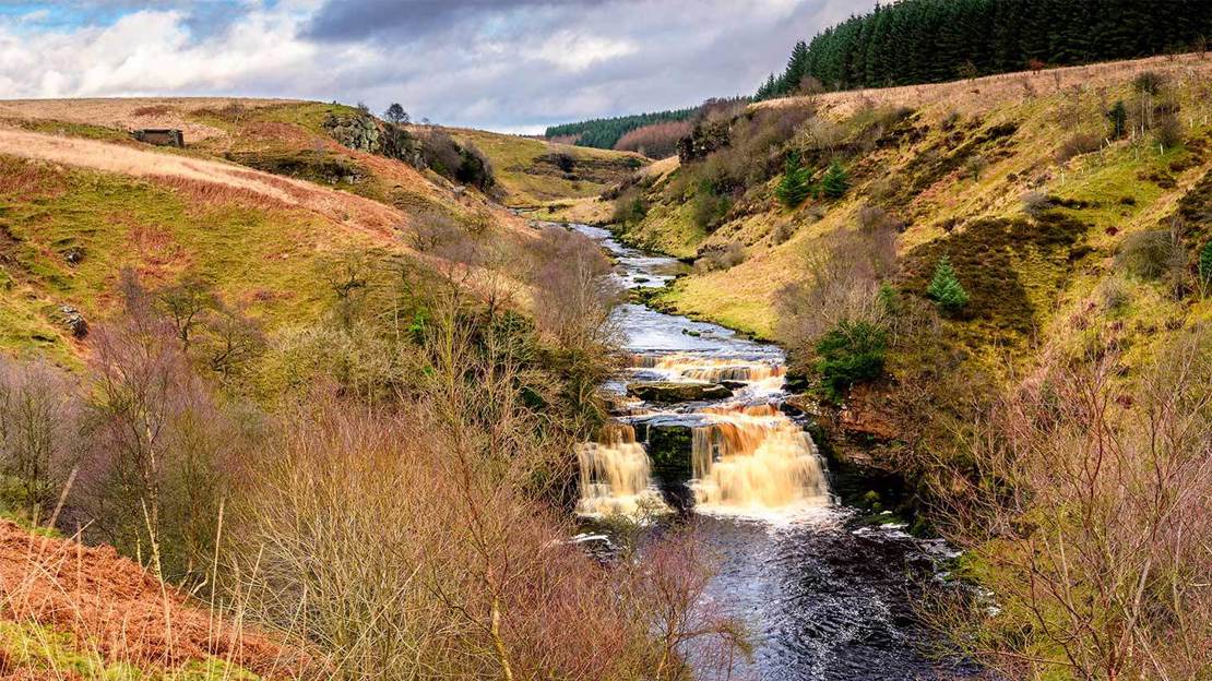 Aerial view of waterfall along a river in a valley