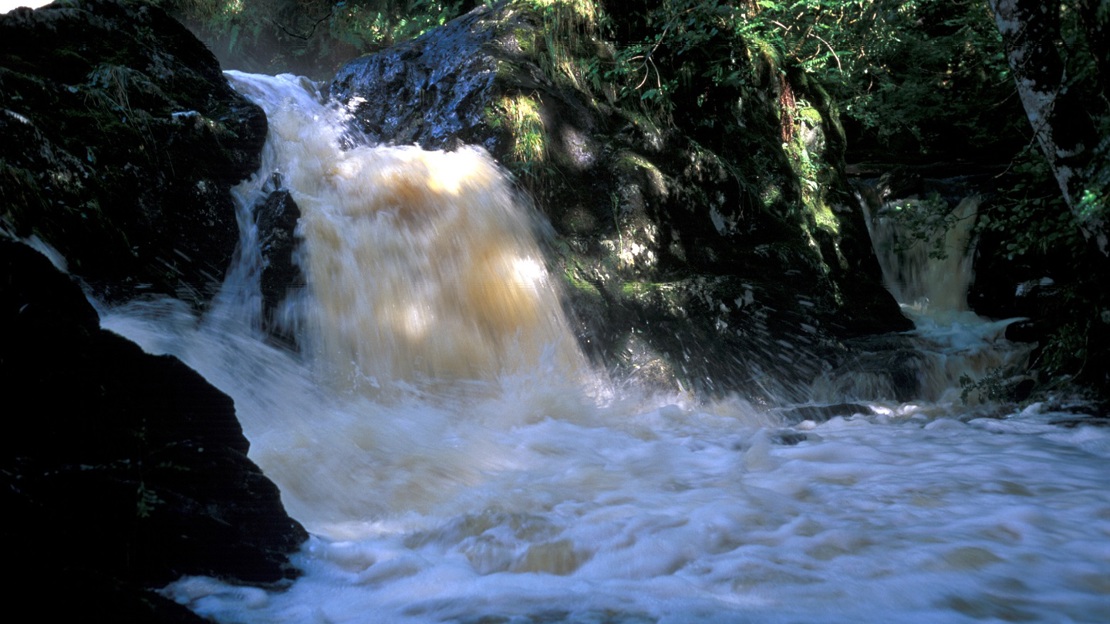 Small powerful waterfall over dark rocks