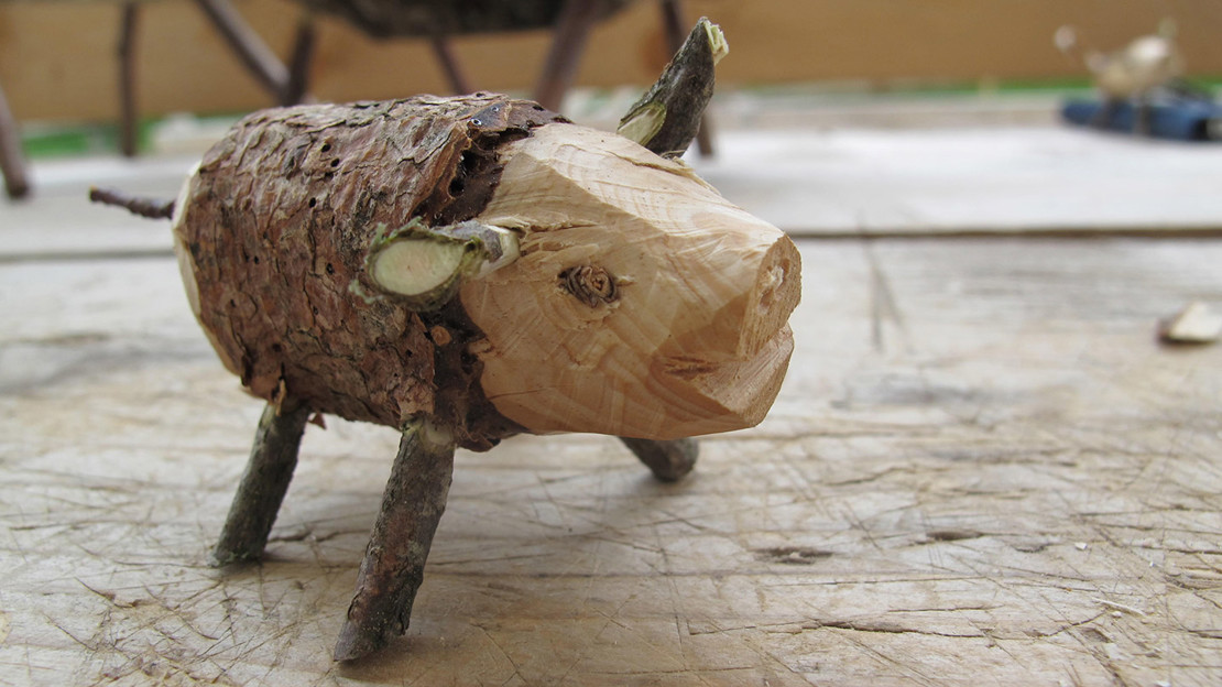 Carved wooden pig with twigs for legs