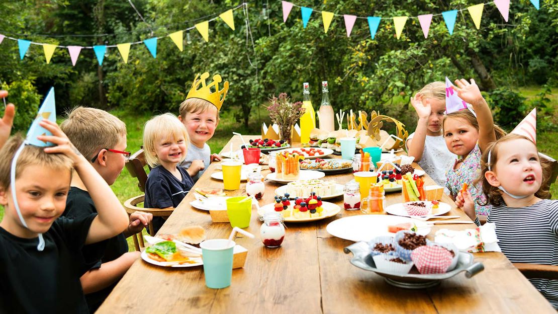 Children sat around table at an outdoor party