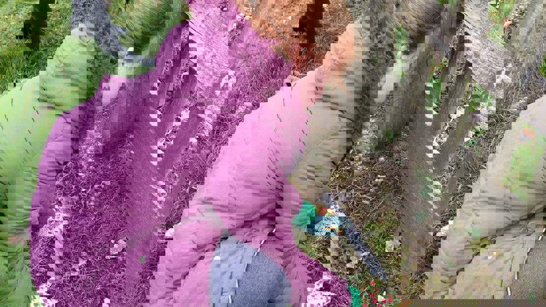 Pupil in purple coat measures the planting area with a ruler on the ground