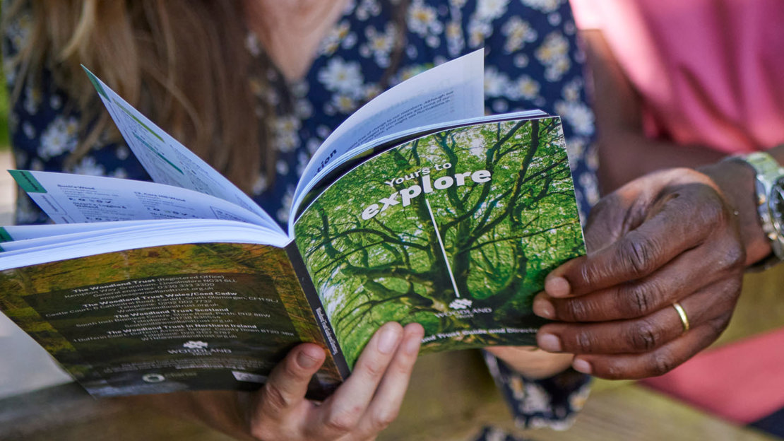 Close-up of a couple's hands holding the Woodland Trust woodland directory