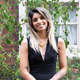 Head and shoulders shot of Woodland Trust trustee, Amber Thiara, with a background of tree branches