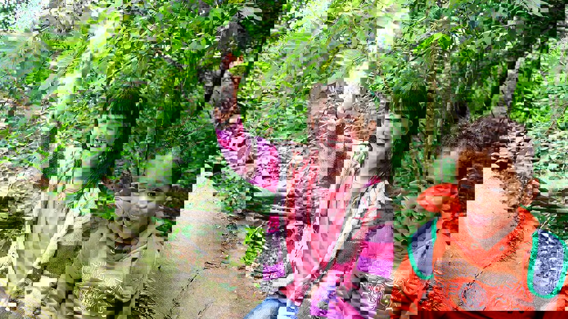 Two smiling children sitting on a log in the woods