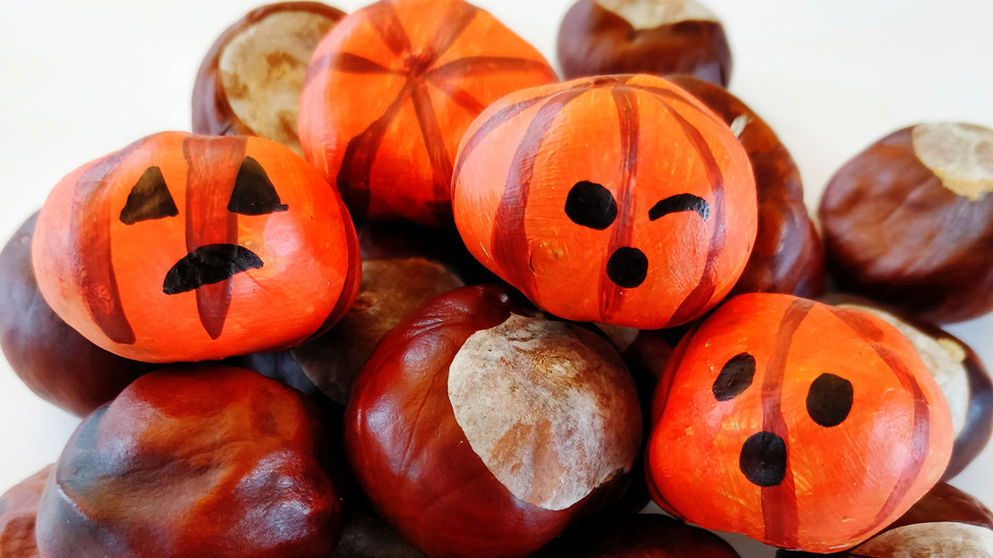 A pile of conkers painted to look like pumpkin jack o'lanterns