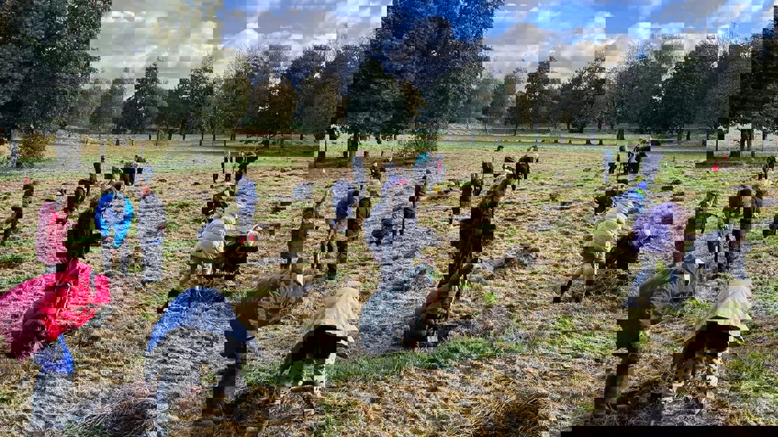 Schoolchildren in coats and wellies planting trees on former golf course land