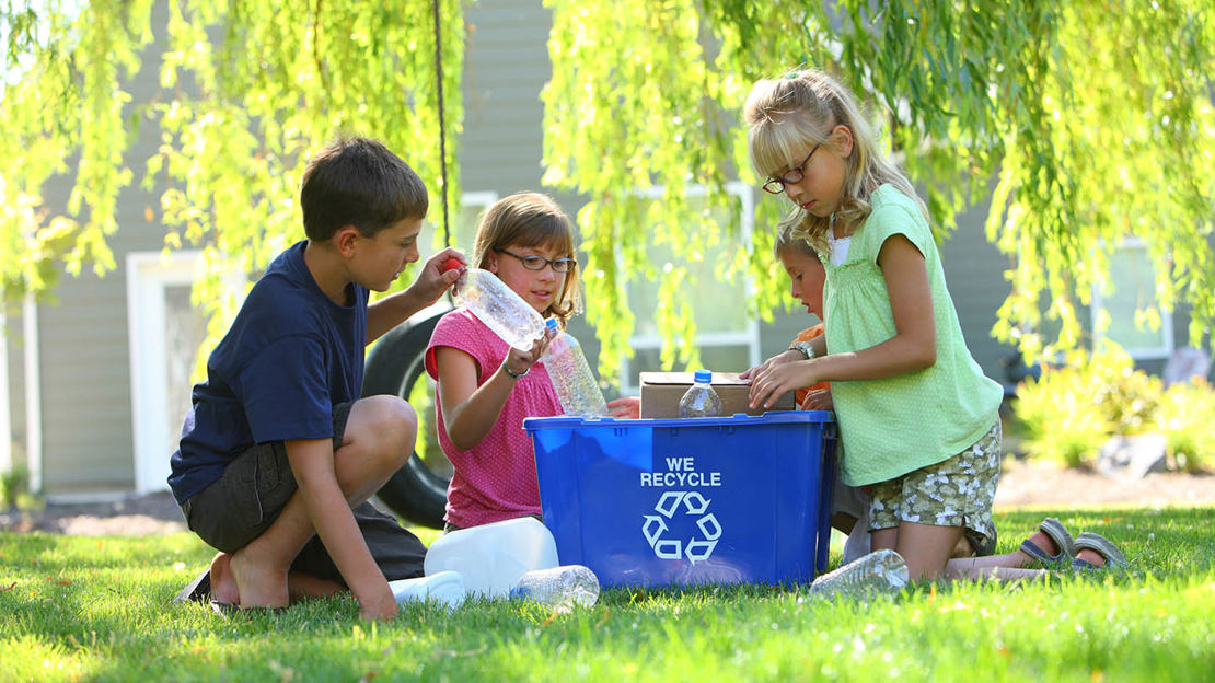 Three children recycling in garden