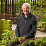 Head and shoulders shot of Lord Tony Hall against a backdrop of wood and leaves
