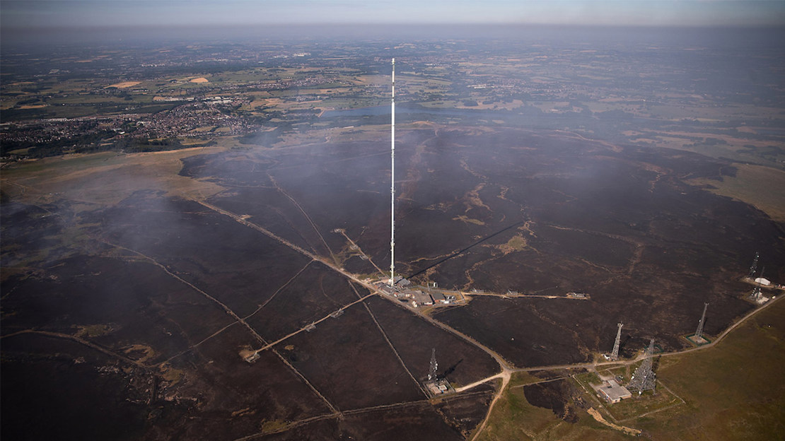 Aerial shot of large TV mast on burnt moorland.