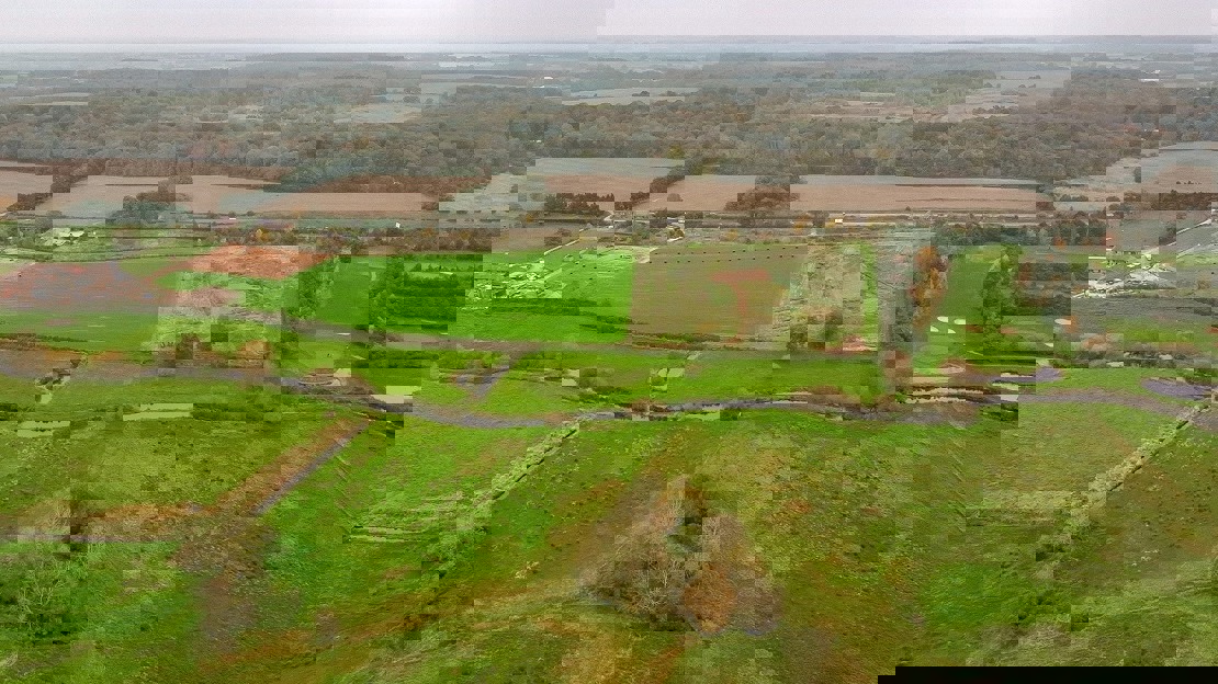 Aerial view of a river and road running through fields and woodland in the background