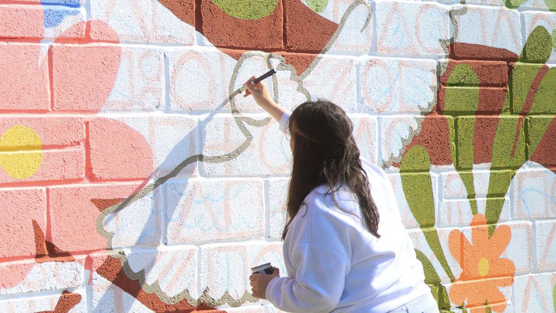 Person painting barn owl on wall.